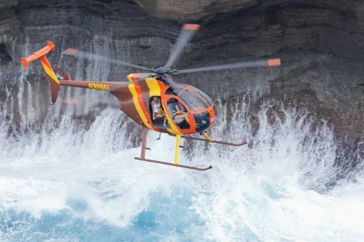 a helicopter tour flying by a waterfall